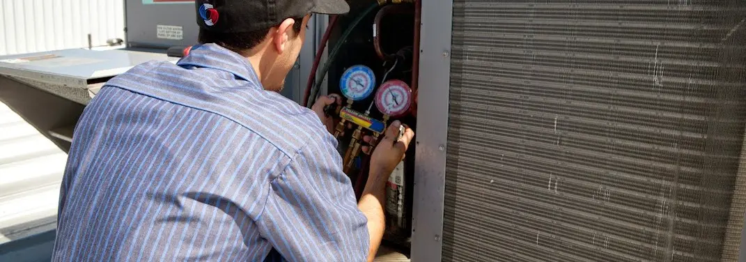 HVAC technician servicing a condenser unit in Macedon